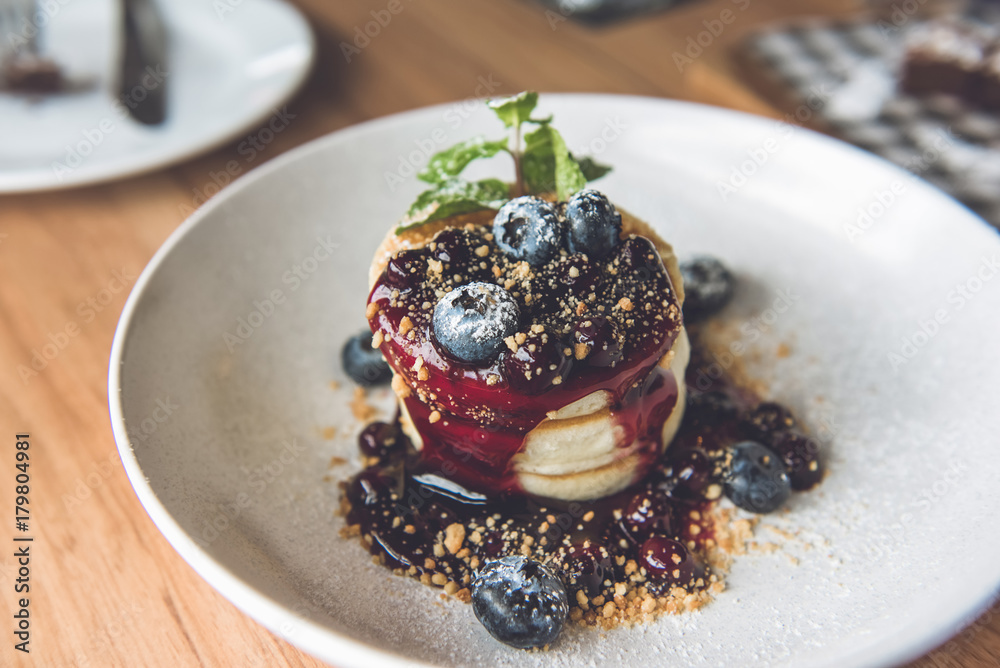 Beautiful appetizing stack of fluffy pancakes topped with fresh blueberries, syrup and ground biscuit Beautiful appetizing stack of fluffy pancakes topped with fresh blueberries, syrup and ground biscuit