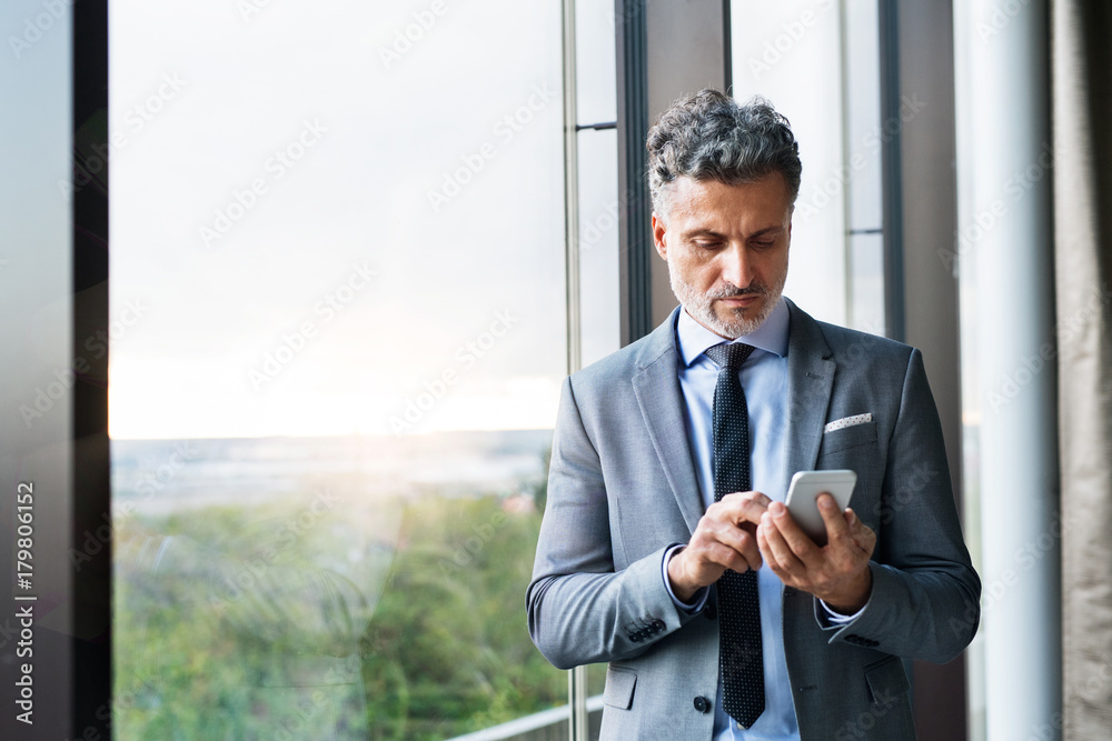 Mature businessman with smartphone in a hotel. Mature businessman with smartphone in a hotel.