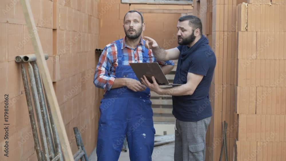 Man with laptop talking to his worker about home project at construction site
Man with laptop talking to his worker about home project at construction site