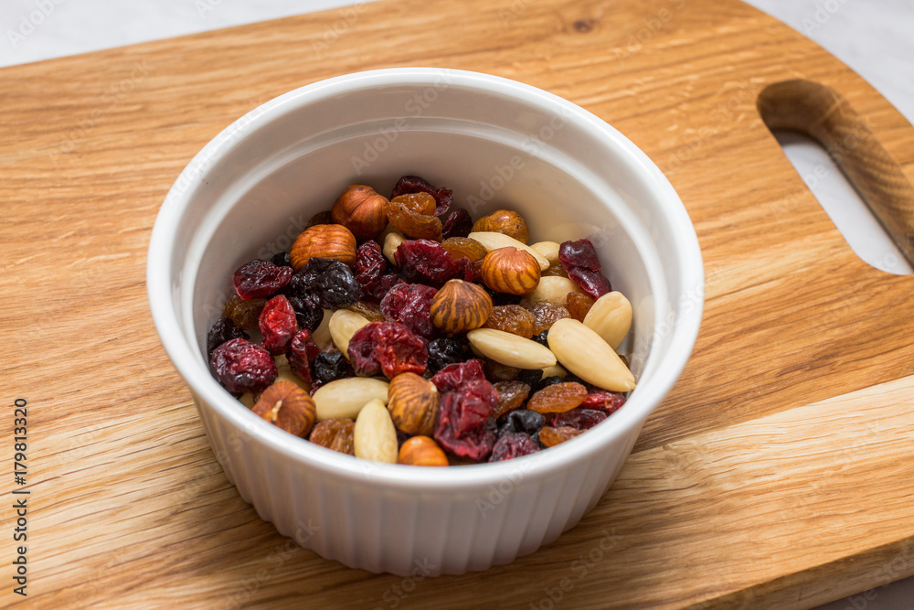 Mixed nuts with cranberries and raisins in white bowl on cutting board Mixed nuts with cranberries and raisins in white bowl on cutting board