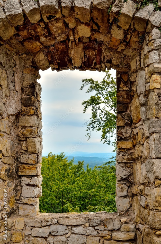 Window overlooking the green trees and mountains in the ruins of the castle. Old Lipowiec castle in Babice, Poland.