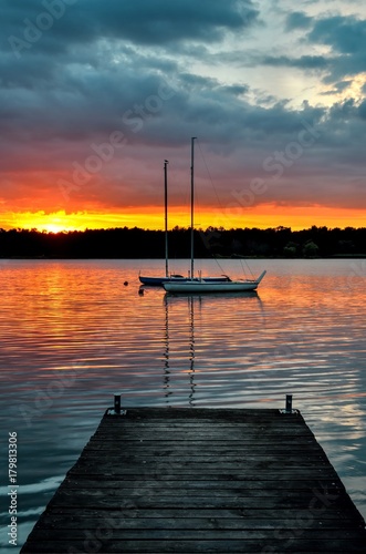 Beautiful summer evening landscape. Wooden pier and boat on the lake at sunset.