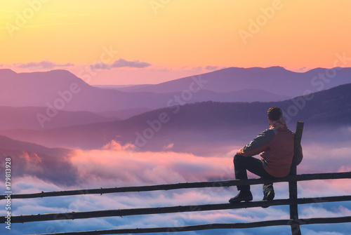 Man on a fence enjoying the sunset