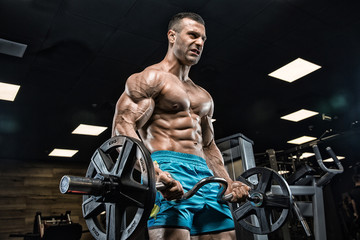Brutal handsome Caucasian bodybuilder working out training in the gym gaining weight pumping up muscles and poses fitness and bodybuilding concept
