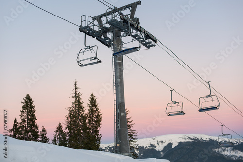 Ski lift chairs on winter resort against a beautiful sky at sunset. Carpathian Mountains, Bukovel, Ukraine