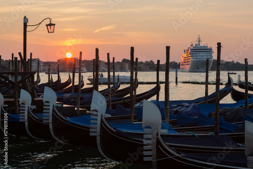 Gondolas and a large cruise ship on Grand Canal in Venice at sunrise