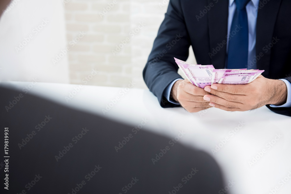 Businessman counting money, Indian Rupee currency, just received from his partner Businessman counting money, Indian Rupee currency, just received from his partner