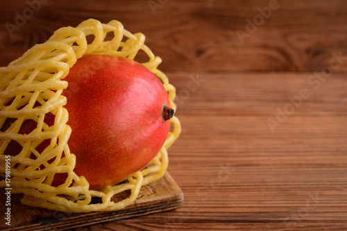 Photography Ripe tasty mango on a brown wooden background with empty space for text