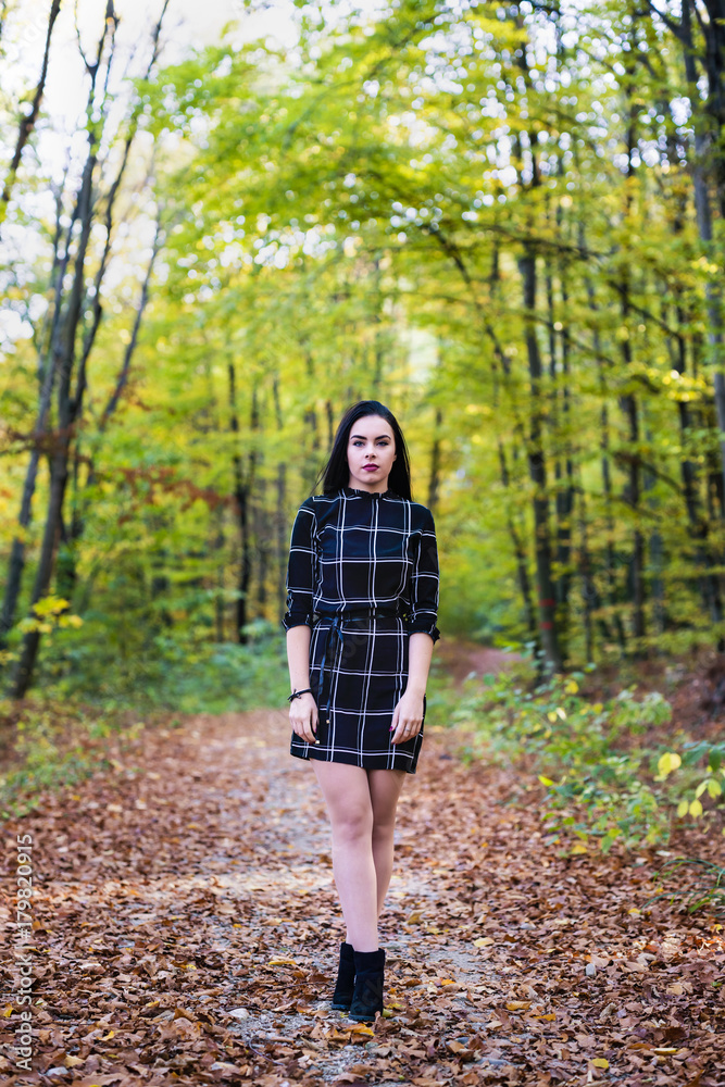 A beautiful and elegant brunette posing in the forest during autumn