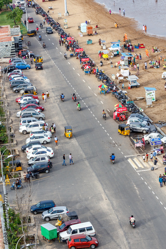 A scene from top of light house at marina beach. Birds eye view of main road with vehicles moving and shadow of the moving vehicles.