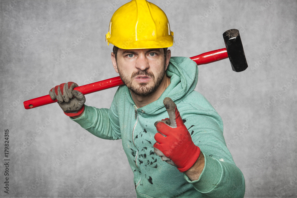 A worker with a big hammer threatens his finger A worker with a big hammer threatens his finger