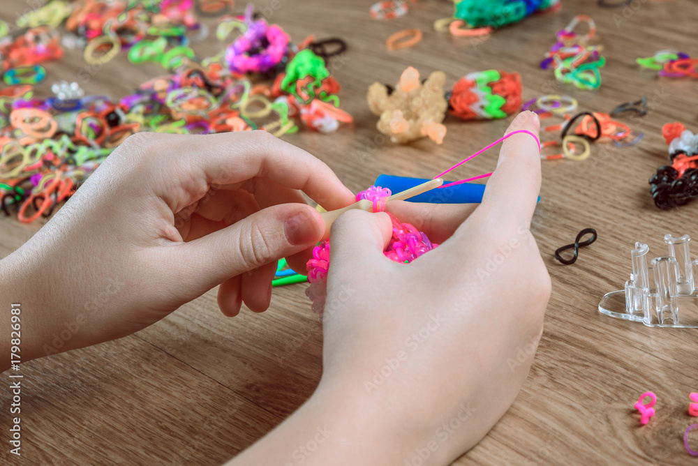 Children's hands closeup weaving crafts from colored rubbers, education and entertainment Children's hands closeup weaving crafts from colored rubbers, education and entertainment