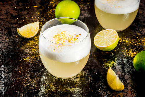 Peruvian, Mexican, Chilean traditional drink pisco sour liqueur, with fresh lime, on rusty black table, copy space