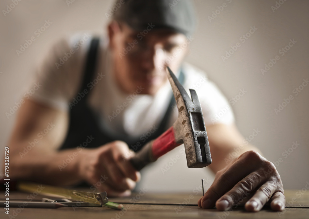 Carpenter hammering a nail - obrazy, fototapety, plakaty 