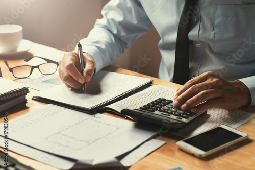 businessman working on desk office with using a calculator to calculate the numbers, finance concept photo