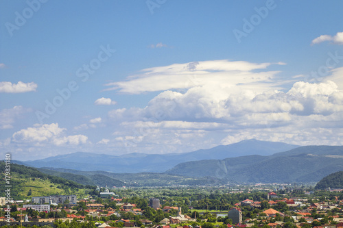 Beautiful summer landscape with city, mountains and cloudy blue sky
