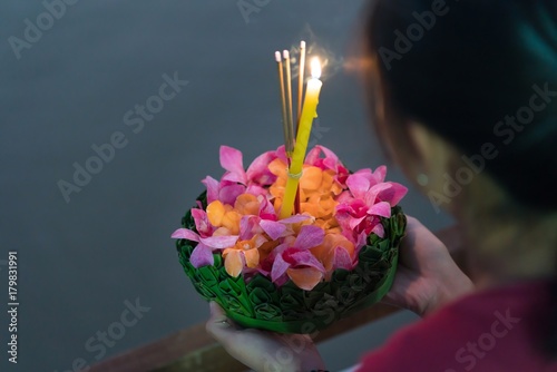 Woman holding decorated float (Krathong) with candles and 
joss sticks are given for Thailand traditional Loy Krathong Festival at the full moon night. photo