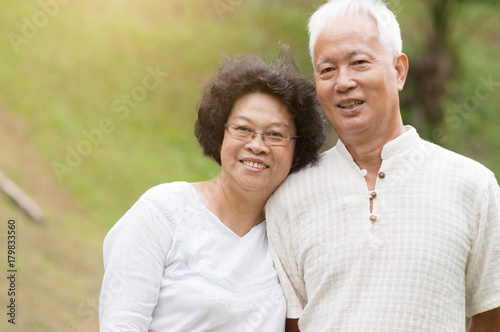 Elderly Asian couple smiling outdoor.