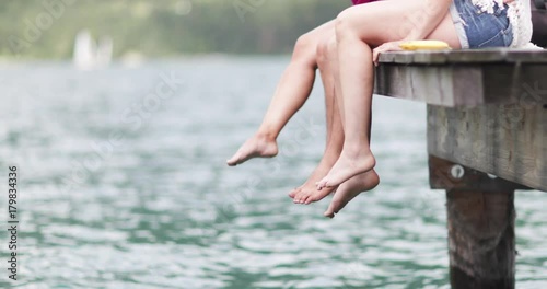 Friends dangling feet over jetty