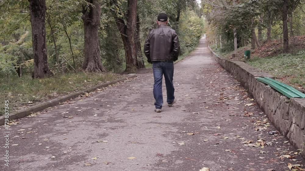 Man walking on the alley in the autumn park Man walking on the alley in the autumn park