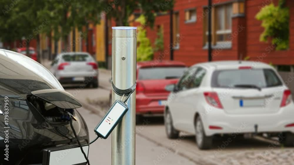 Electric car is charged in the parking lot near the house. The charging process indicator flashes. 4K video. Electric car is charged in the parking lot near the house. The charging process indicator flashes. 4K video.
