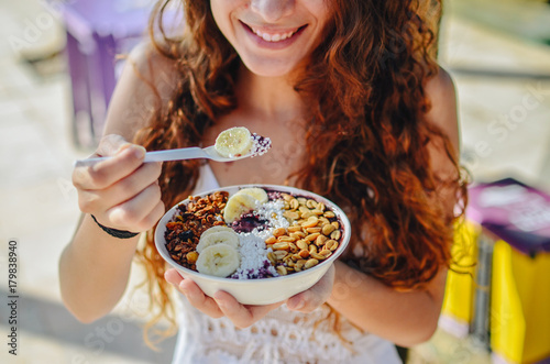 Acai bowl woman eating morning breakfast at cafe. Closeup of fruit smoothie healthy diet for weight loss with berries and oatmeal. Organic raw vegan healthy food. photo