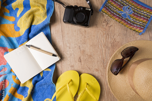 Overhead view of beach accessories for a summer trip on wooden table with copy space. Vacation and travel concept.