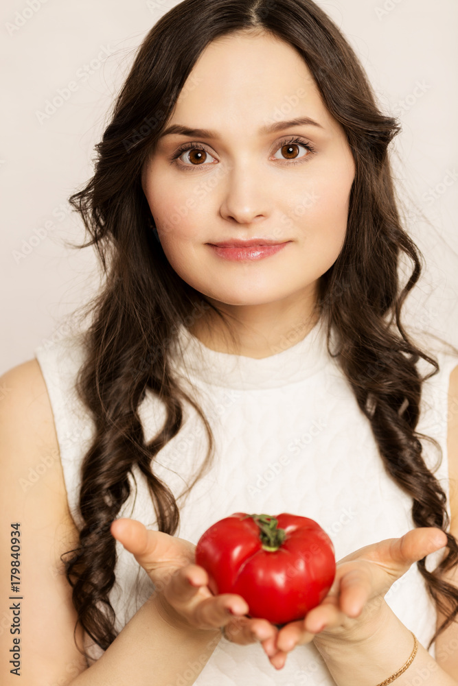 Young beautiful woman, brunette, with big tomato, close-up Young beautiful woman, brunette, with big tomato, close-up