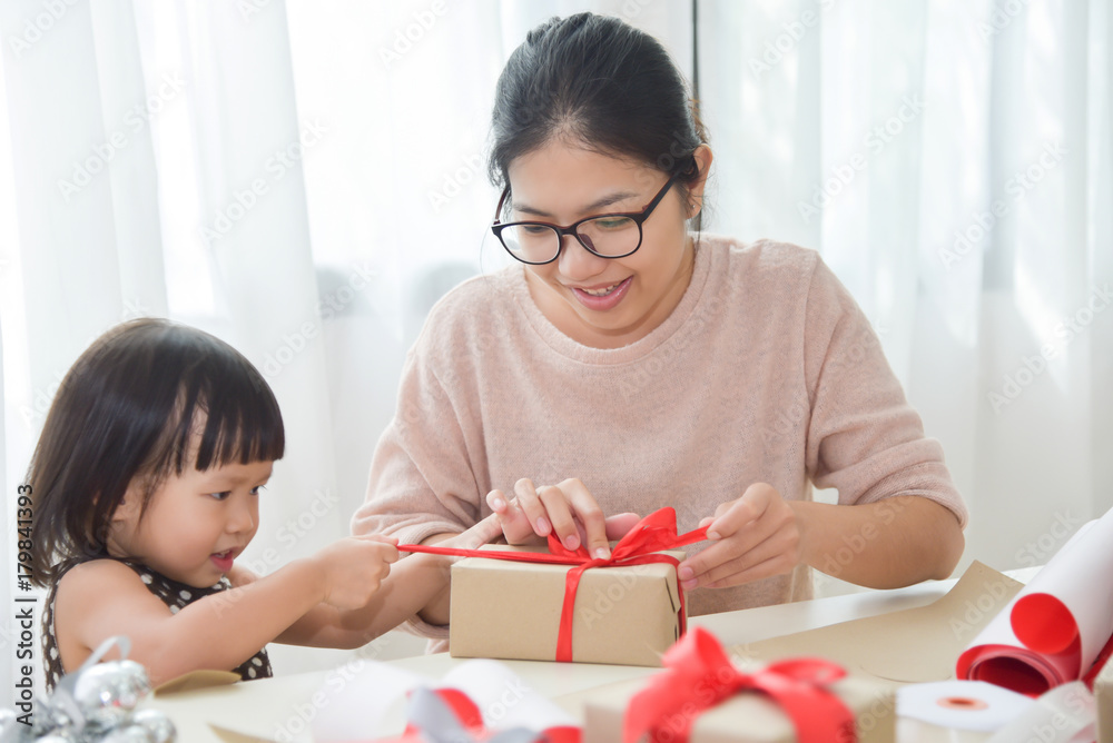 Young mother and her daughter wrapping a gift box. Young mother and her daughter wrapping a gift box.