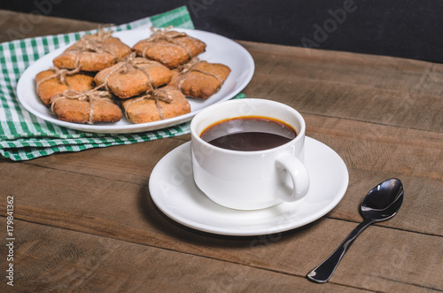 Black coffee in a white cup on a green napkin and homemade cookies.