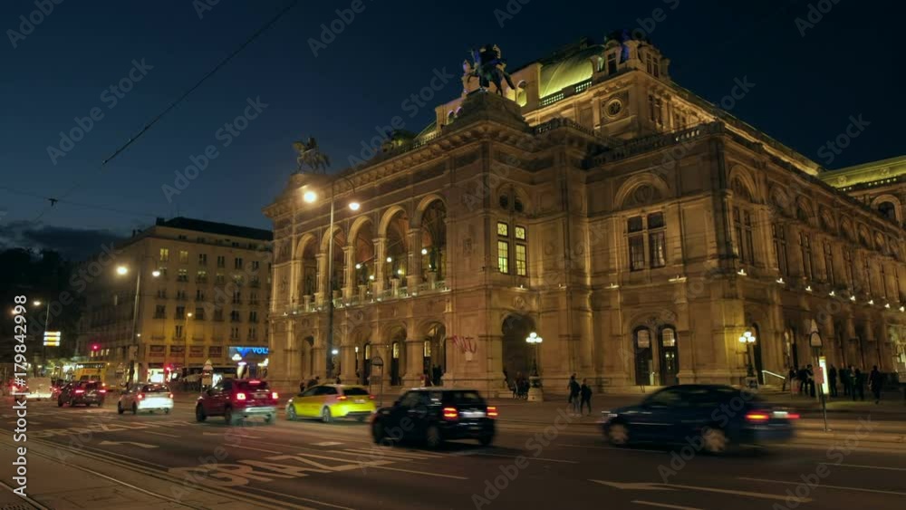 Static wide night shot of traffic passing in front of the Vienna Opera House on Opernring. Taken in September as the city lights are coming on Static wide night shot of traffic passing in front of the Vienna Opera House on Opernring. Taken in September as the city lights are coming on