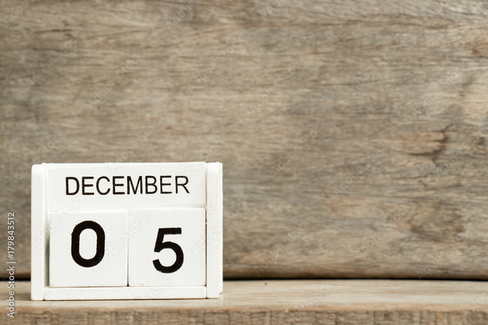 White block calendar present date 5 and month December on wood background