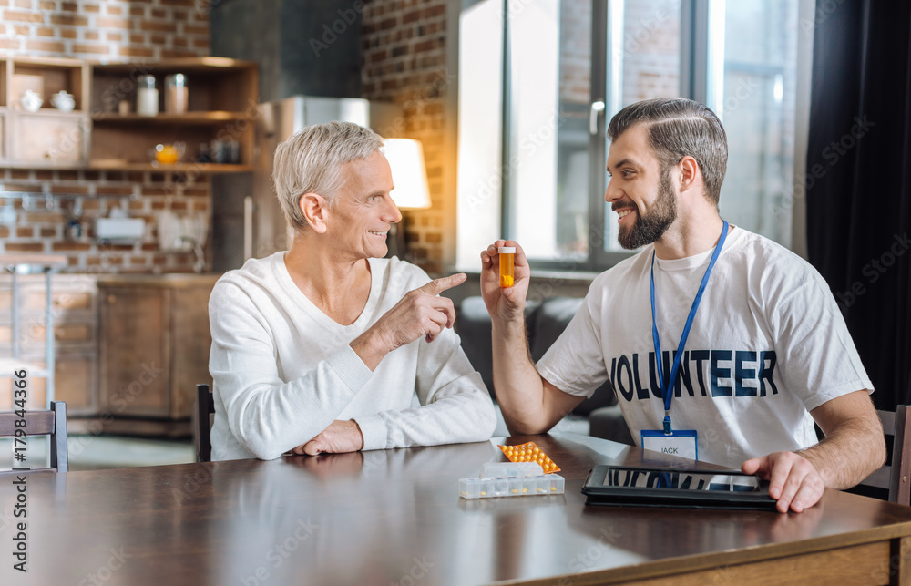 Good pills. Kind attentive enthusiastic volunteer looking cheerful while recommending a senior man to take a box of medicine Good pills. Kind attentive enthusiastic volunteer looking cheerful while recommending a senior man to take a box of medicine