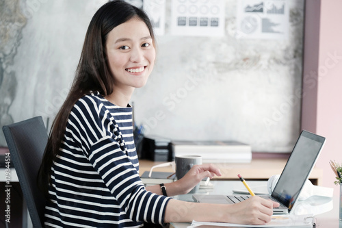 Wallpaper Mural Young asian businesswoman working with laptop with smiling face at office desk, positive emotion, office life concept Torontodigital.ca
