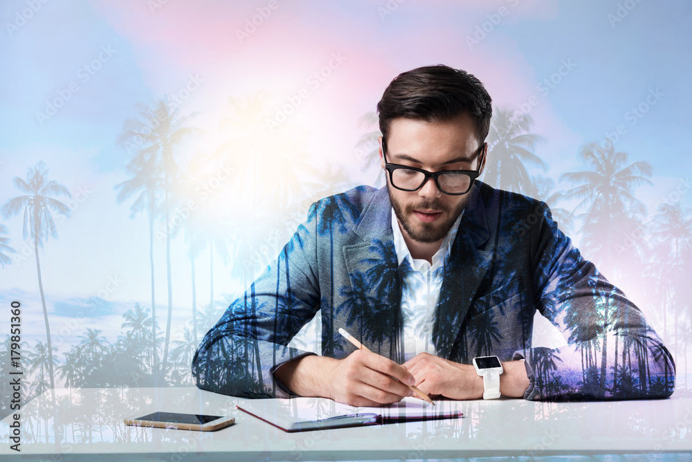 Concentration. Smart scrupulous experienced worker sitting at the table and looking concentrated while writing a report Concentration. Smart scrupulous experienced worker sitting at the table and looking concentrated while writing a report