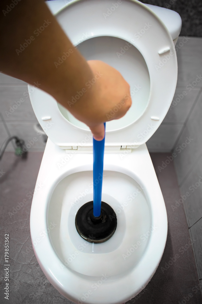 Plunger Clearing a Clogged Toilet in the Bathroom. Stock Photo Adobe