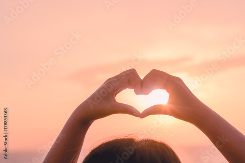 Female hands in the form of heart against sunlight in sunset sky  twilight time. Hands in shape of love heart  Love concept.