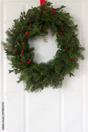 Handmade is a Christmas wreath made of spruce, thuja, juniper, boxwood and wild rose berries adorning the front door. photo