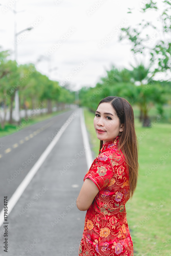 Naklejka premium happy Chinese new year. Asian woman wearing traditional Cheongsam clothes portrait outdoor