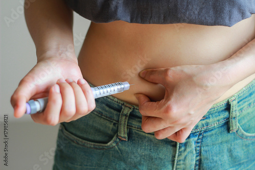 A diabetes patient is injecting insulin pen by herself.
