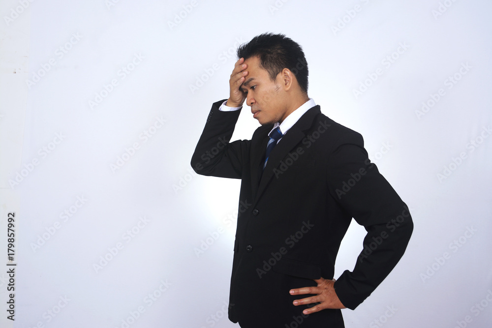 Depressed Asian Businessman holding head in hands Depressed Asian Businessman holding head in hands