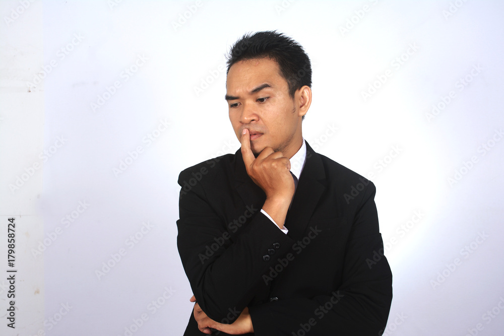 Asian businessman thinking while put the finger on the mouth Asian businessman thinking while put the finger on the mouth