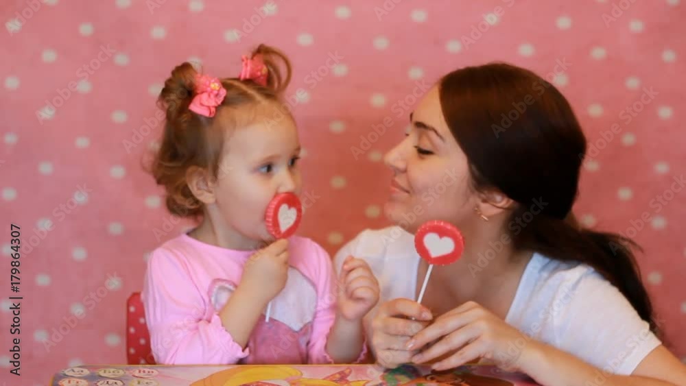 The mother hugs and plays with her child. Mom and daughter eat sweets and play a game, expressing different emotions, smiling at each other The mother hugs and plays with her child. Mom and daughter eat sweets and play a game, expressing different emotions, smiling at each other
