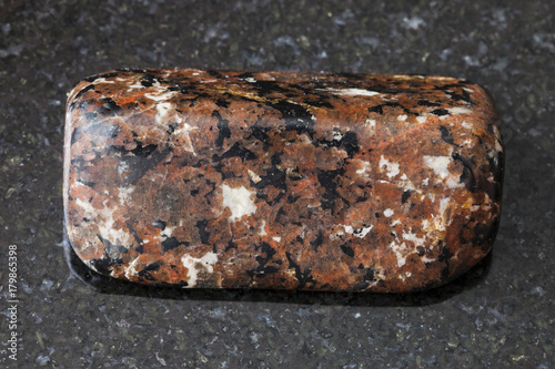polished spreusteined urtite stone on dark photo