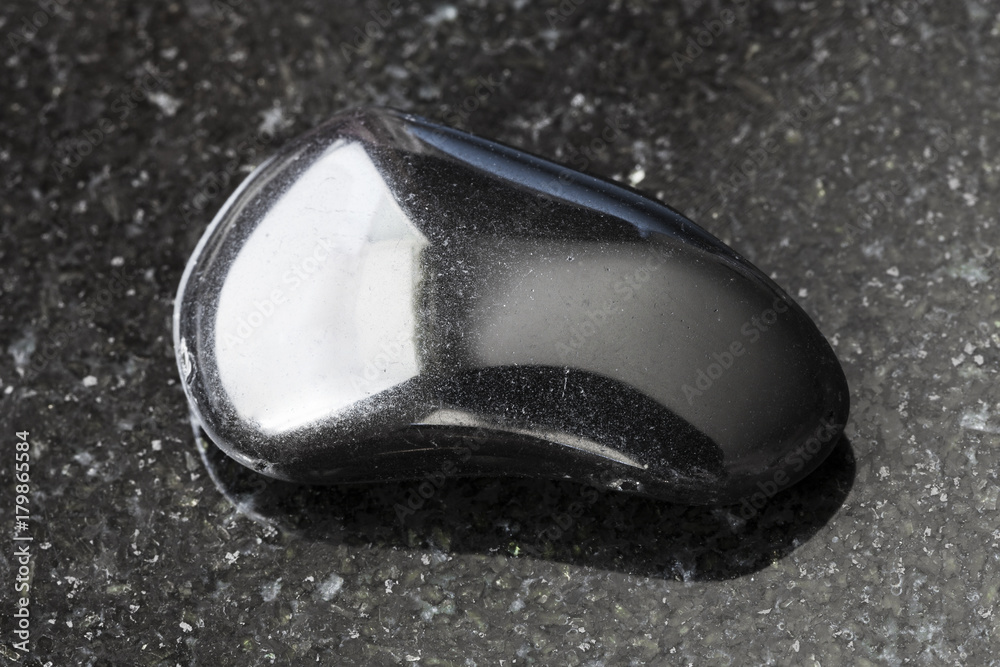 polished black obsidian gemstone on dark polished black obsidian gemstone on dark