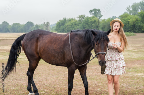 Girl in a hat and summer dress with a horse / Photographed in Russia, at the racetrack in Orenburg