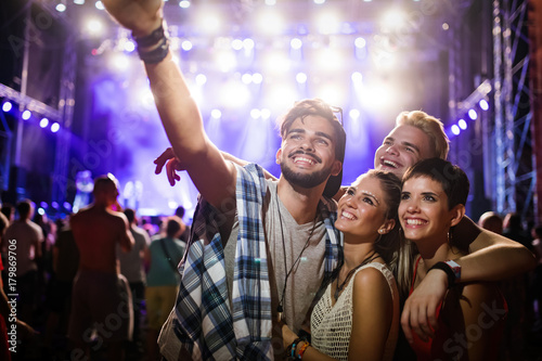 Happy friends taking selfie at music festival