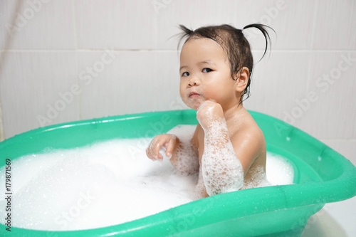 Wallpaper Mural Little asian girl taking bath in bathtub, thinking mode, look serious and thinking something. Bathtub with foam bubbles. Toddler girl taking bath Torontodigital.ca