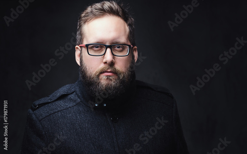 Serious plump male in eyeglasses over grey background.