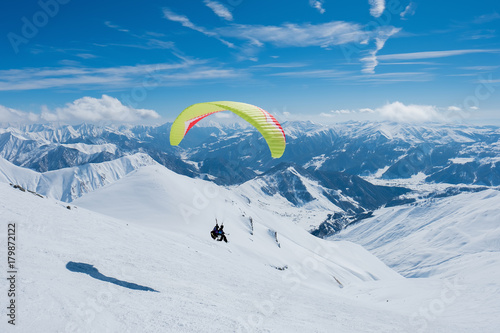Paraglider flying between the jagged snowy peaks